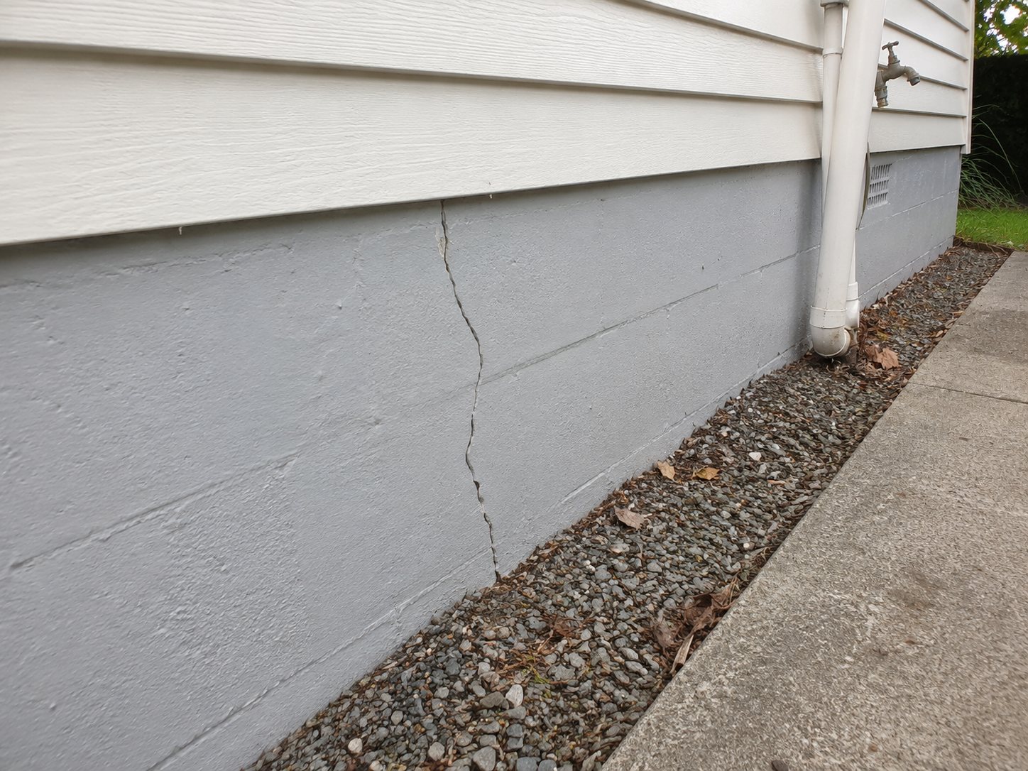 Stepped crack along the block foundation beside the path, with downpipe and drainage strip alongside