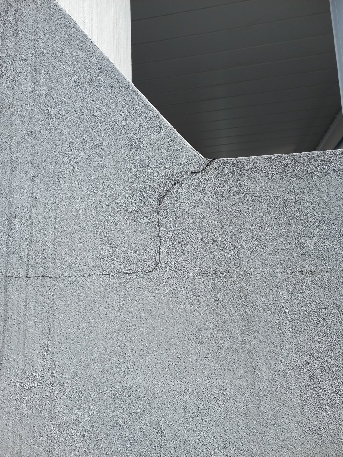Stepped vertical crack in the painted block foundation near a corner of the house